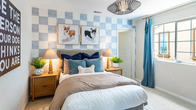 a bed sitting in a bedroom next to a window and a chandelier