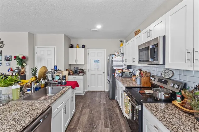 a kitchen with granite countertop lots of clutter and stainless steel appliances