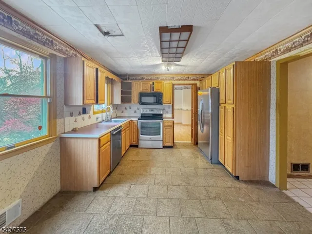 a large kitchen with stainless steel appliances granite countertop a stove a sink dishwasher and a refrigerator