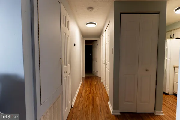 a view of a hallway with wooden floor and closet