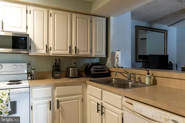 a kitchen with granite countertop a sink a stove and cabinets