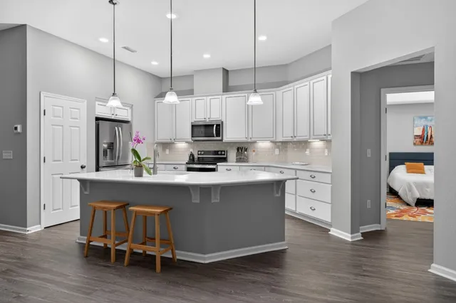 a kitchen that has a lot of cabinets in it and wooden floors