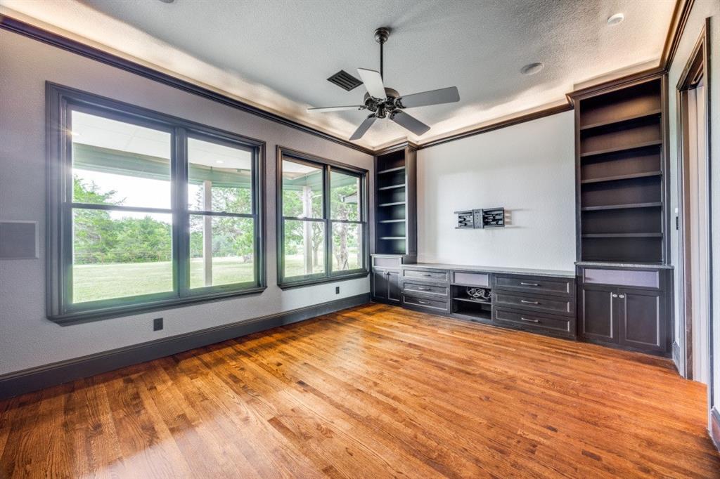3244 Joe Davis Road Whitewright, TX 75491 - Photo 12 of 28 Unfurnished living room featuring wood finished floors, healthy amount of natural light, a ceiling fan, built in study area, and a textured ceiling