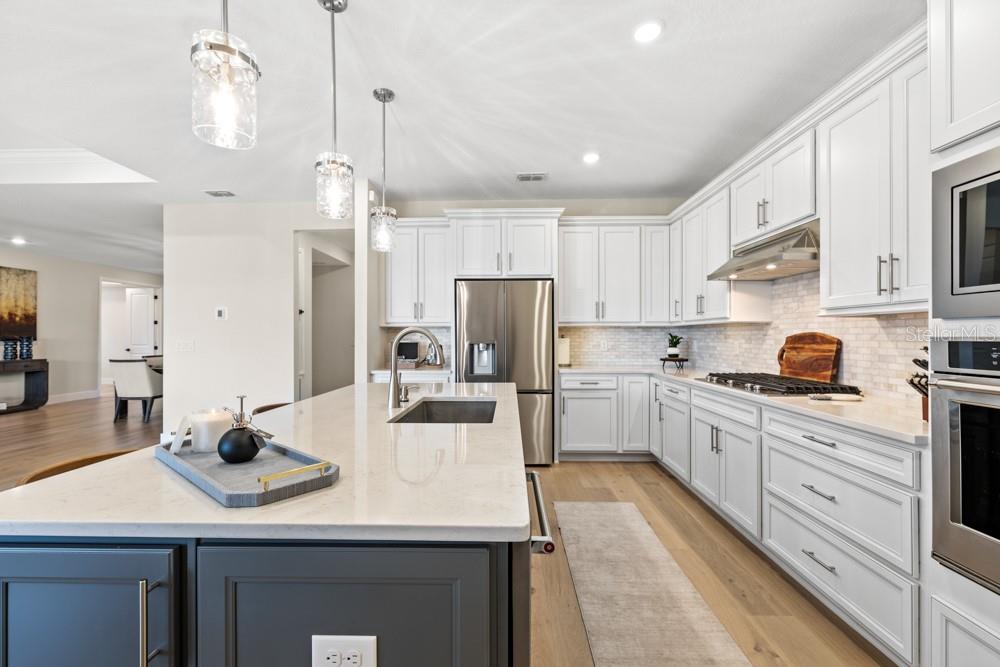 5148 Foothills Preserve Loop Mount Dora, FL 32757 - Photo 3 of 54 a kitchen with stainless steel appliances kitchen island granite countertop a sink dishwasher and white cabinets with wooden floor