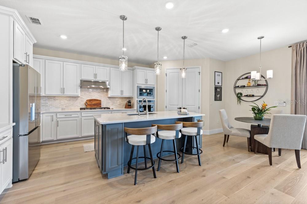 5148 Foothills Preserve Loop Mount Dora, FL 32757 - Photo 6 of 54 a kitchen with stainless steel appliances kitchen island granite countertop a table chairs and a refrigerator