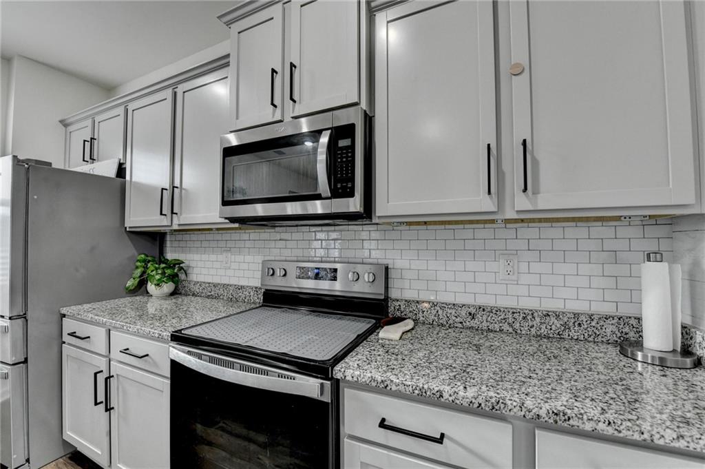 86 Canyon Ferry Way Hoschton, GA 30548 - Photo 12 of 61 a kitchen with stainless steel appliances granite countertop a sink stove and refrigerator