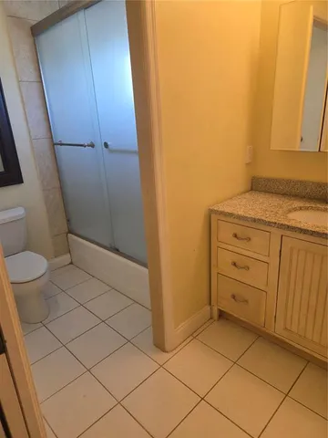 a bathroom with a granite countertop sink and a toilet