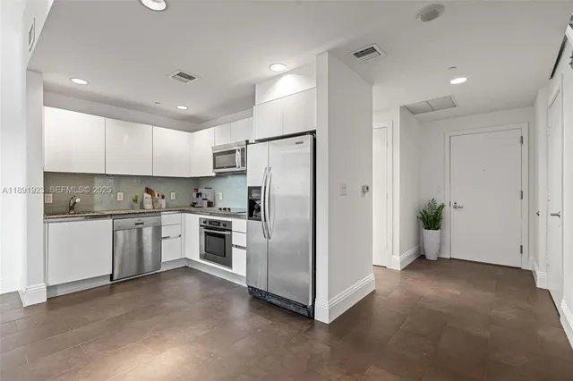 a kitchen with a refrigerator and white cabinets