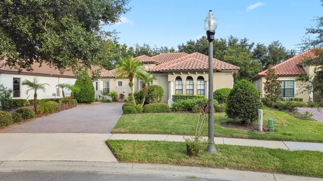 a view of a house with a yard and table and chairs under an umbrella