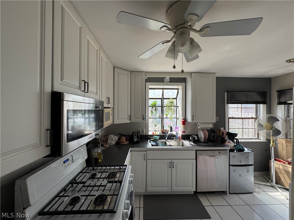 4198 Bushnell Road Cleveland, OH 44118 - Photo 2 of 11 Kitchen featuring white cabinetry with dark hardware, black countertops, stainless steel microwave, and white tile flooring