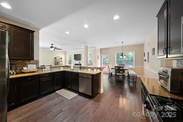 an open kitchen with wooden floor and stainless steel appliances