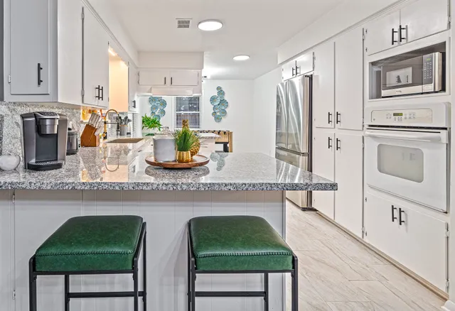 a kitchen with white cabinets and appliances