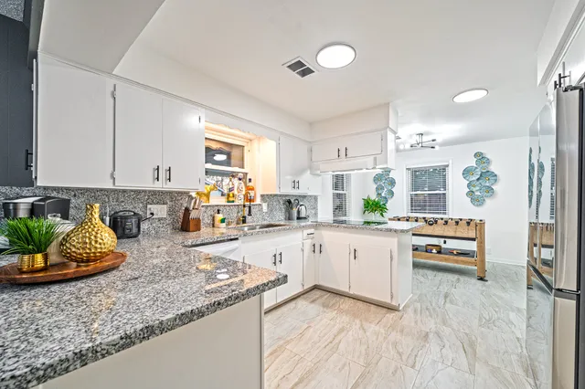 a kitchen with stainless steel appliances granite countertop a refrigerator a stove a sink dishwasher and white cabinets with wooden floor