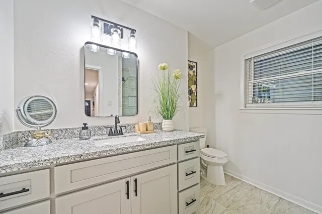 a bathroom with a granite countertop sink a mirror and shower