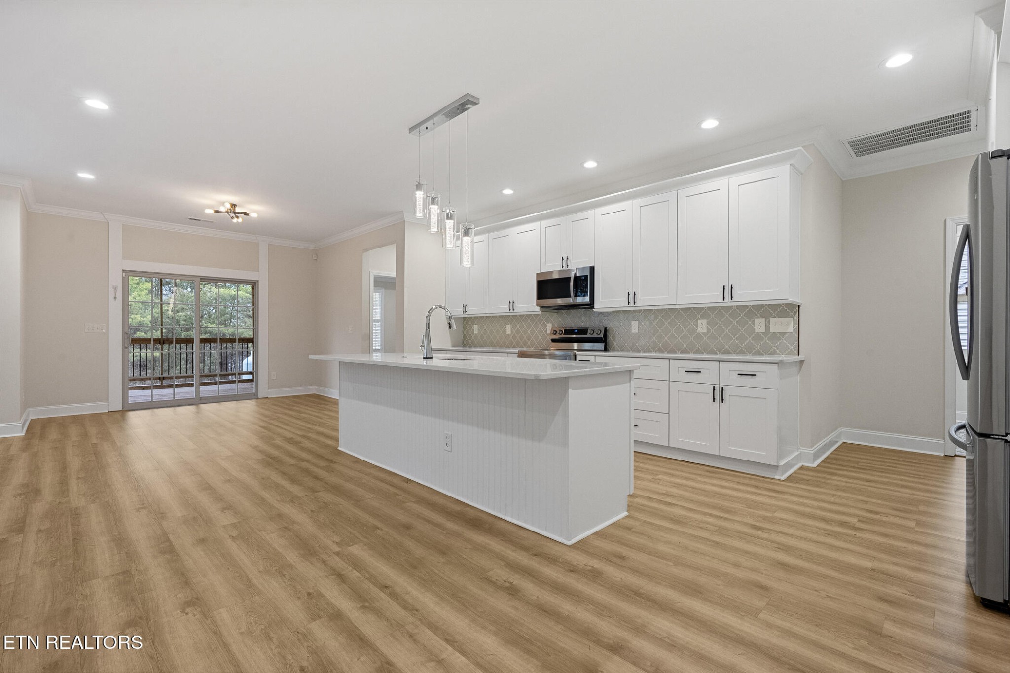 129 Ogana Way Loudon, TN 37774 - Photo 8 of 32 a large kitchen with stainless steel appliances a large counter top a stove a refrigerator cabinets and a wooden floor