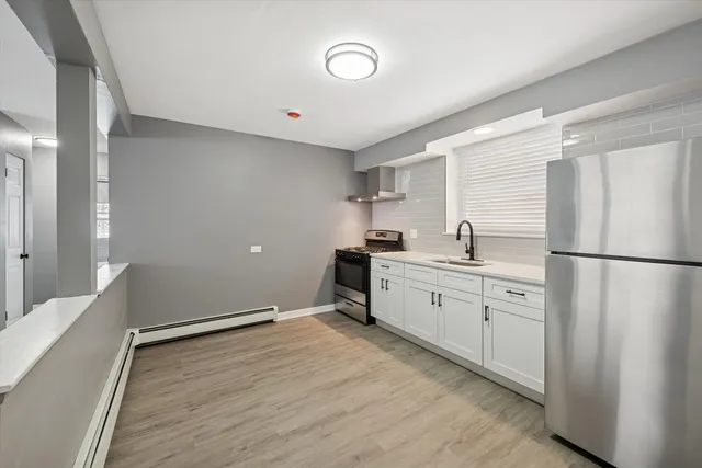 a kitchen with a refrigerator and white cabinets