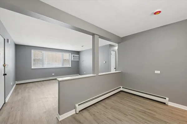 a view of an empty room with wooden floor and a window