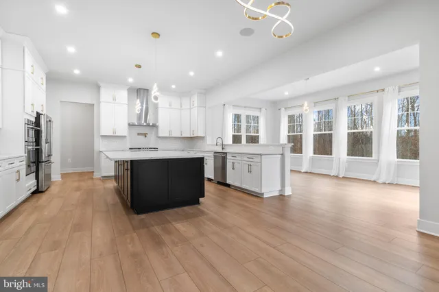 a large kitchen with stainless steel appliances kitchen island a large counter top and a wooden floors