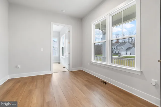 a view of an empty room with wooden floor and windows