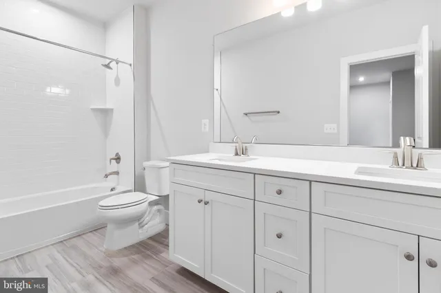 a bathroom with a double vanity sink a toilet and a tub