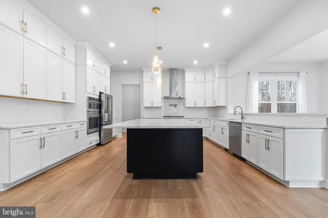 a large kitchen with stainless steel appliances granite countertop a stove a sink dishwasher and a oven with white cabinets