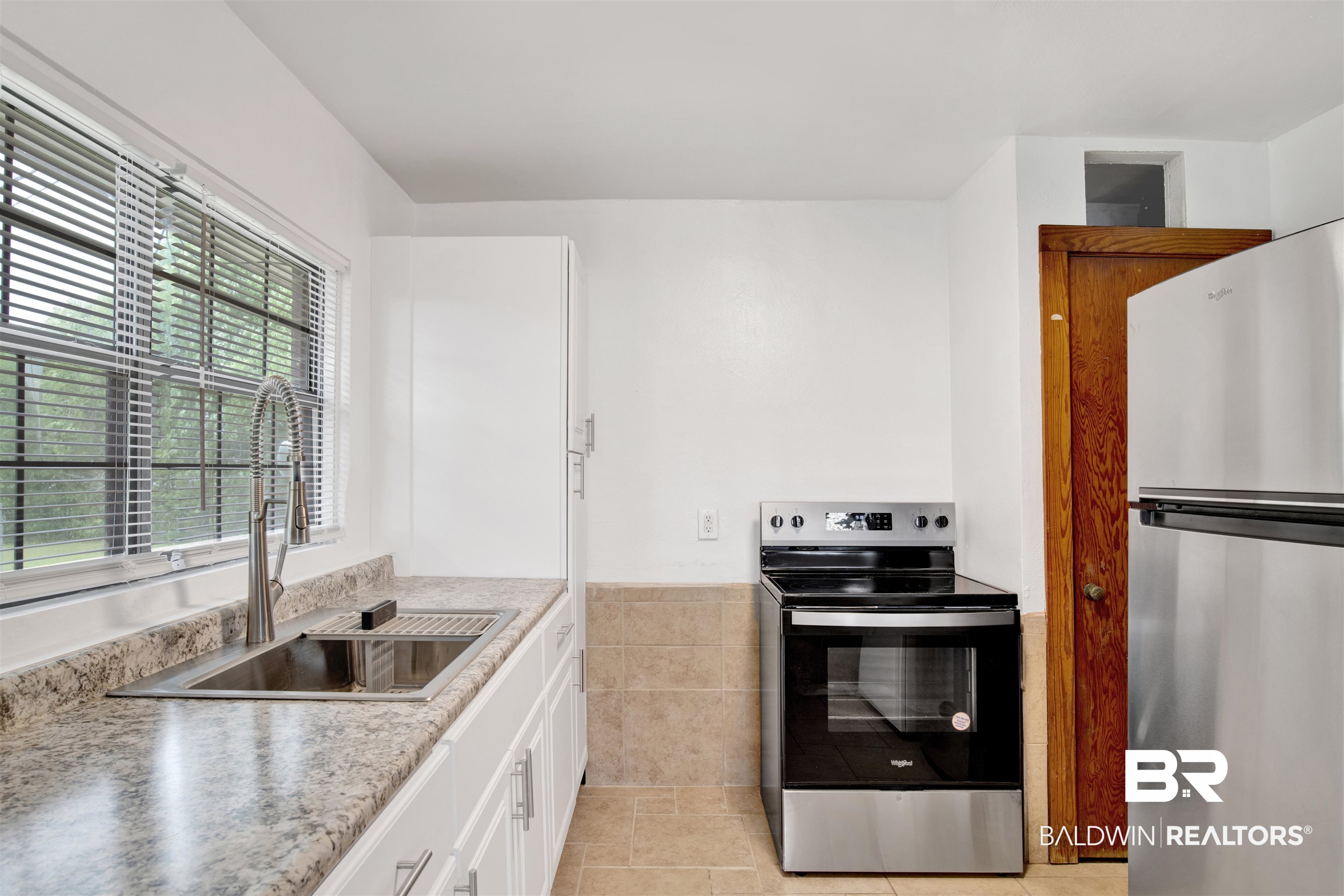 311 West Myrtle Avenue Foley, AL 36535 - Photo 11 of 22 Kitchen with white cabinetry, stainless steel appliances, sink, and light tile patterned floors