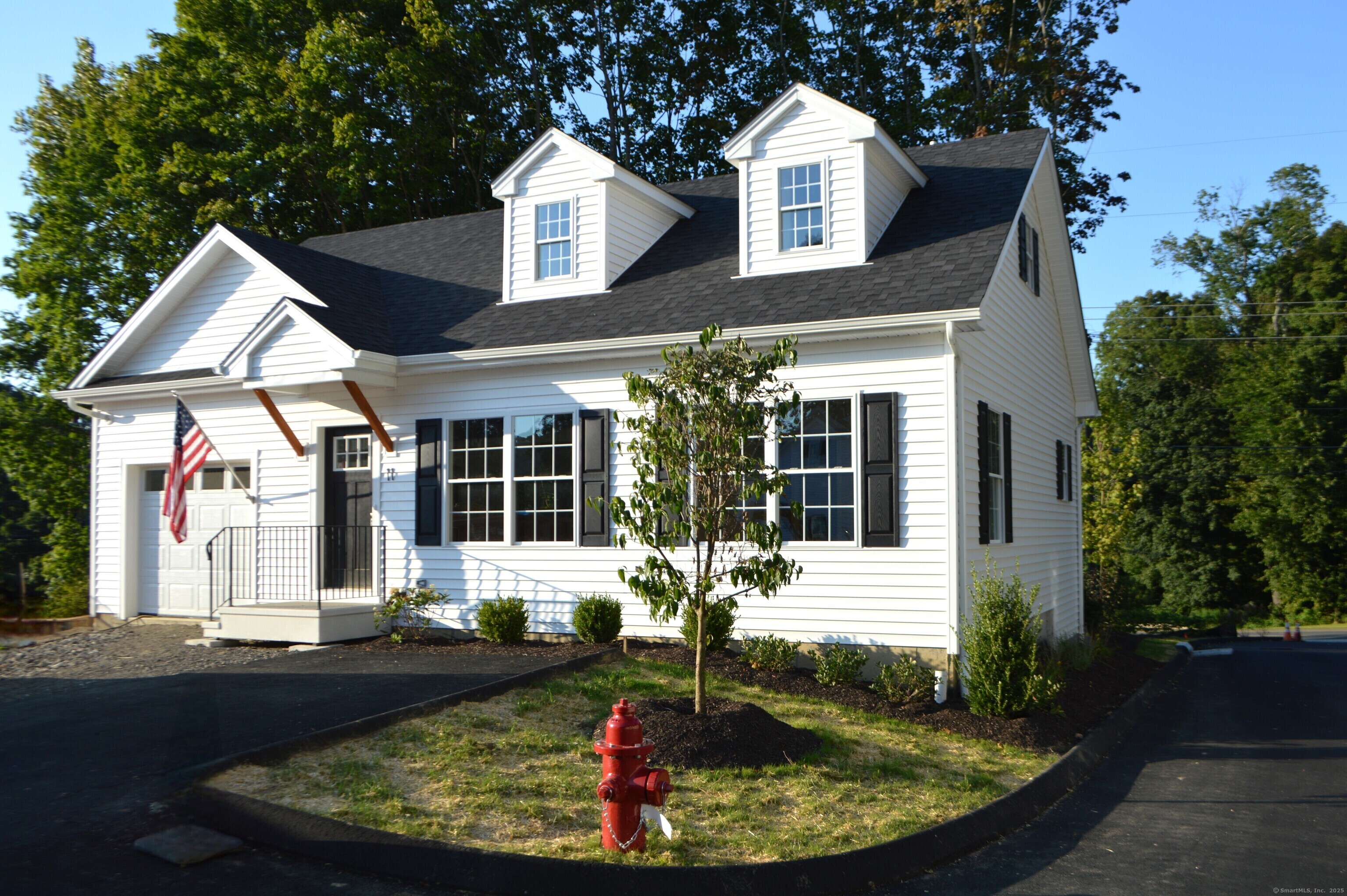 a view of a white house with a small yard and sitting area