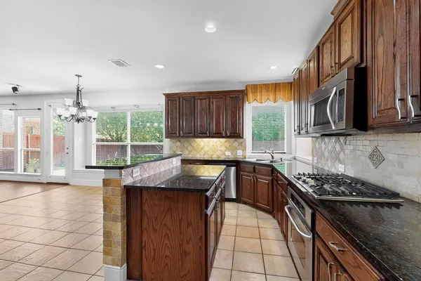 a kitchen with stainless steel appliances granite countertop a stove a sink and a microwave