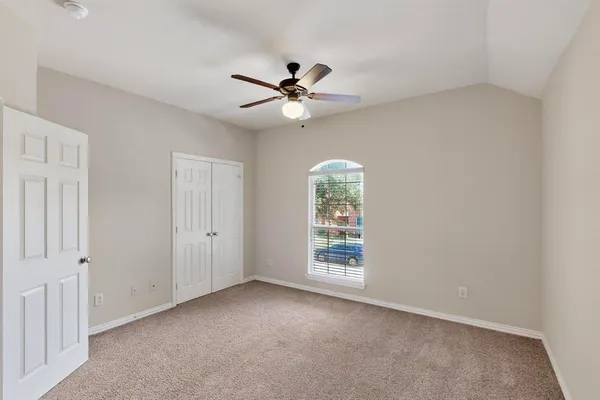 an empty room with windows and fan chandelier fan