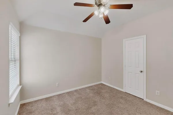 an empty room with a window and a fan