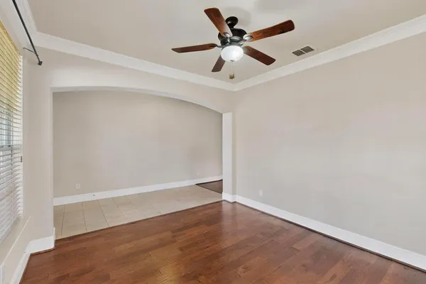 an empty room with wooden floor and a ceiling fan