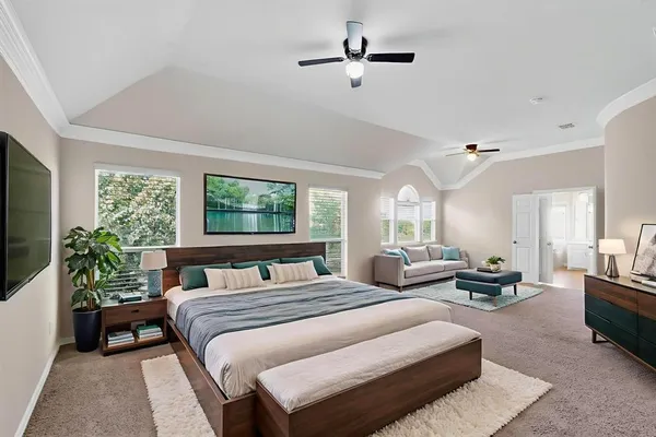 a bedroom with a large bed a flat tv screen and a potted plant