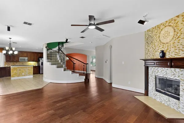 a living room with stainless steel appliances kitchen island a fireplace and a ceiling fan