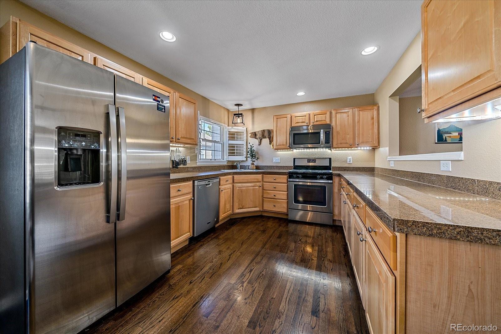 6318 Trailhead Road Highlands Ranch, CO 80130 - Photo 12 of 32 a kitchen with stainless steel appliances granite countertop refrigerator a sink a stove top oven and cabinets