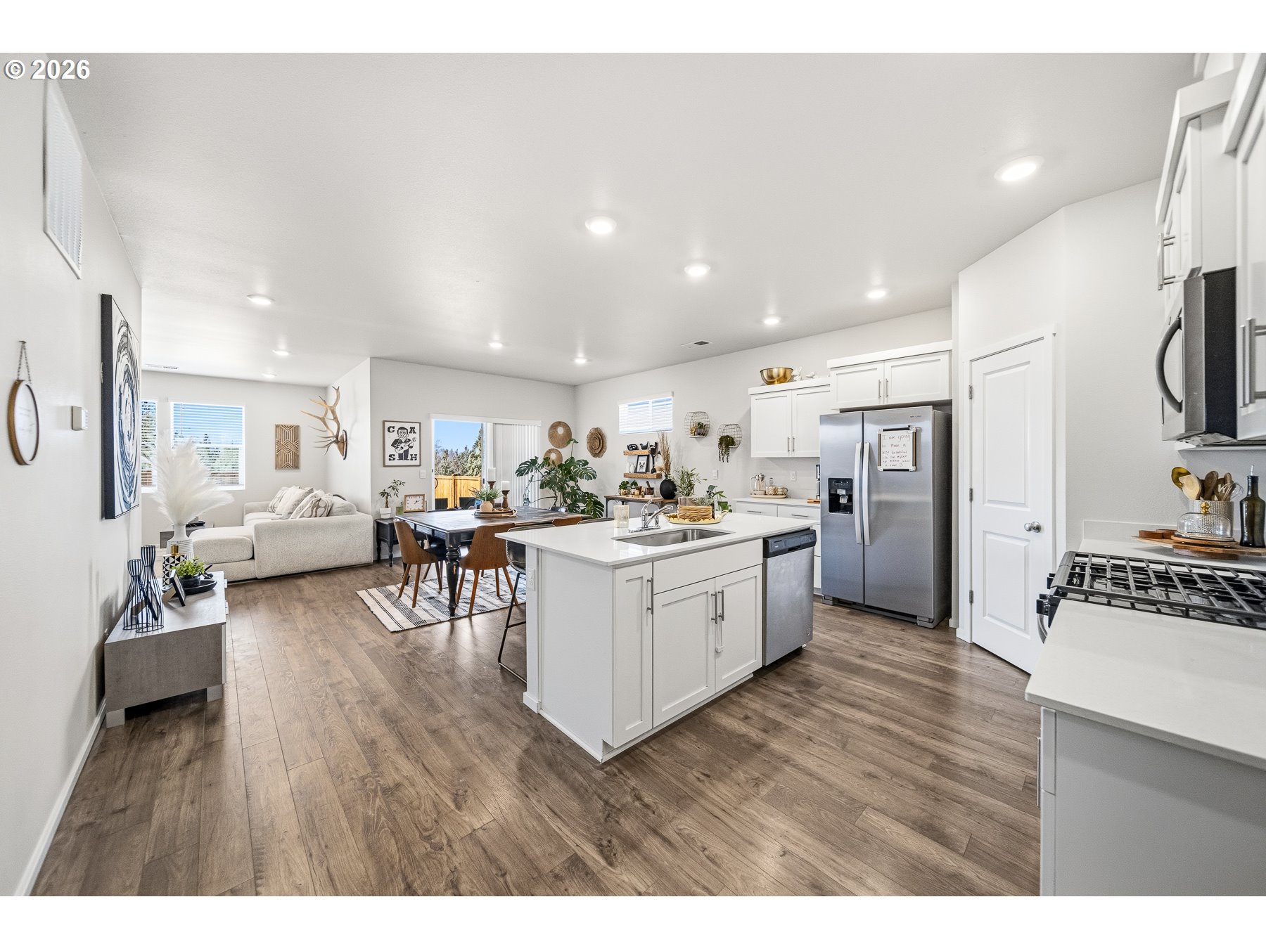 597 Northeast Union Loop Prineville, OR 97754 - Photo 4 of 22 a open kitchen with stainless steel appliances kitchen island granite countertop a refrigerator a sink dishwasher a dining table and chairs with wooden floor