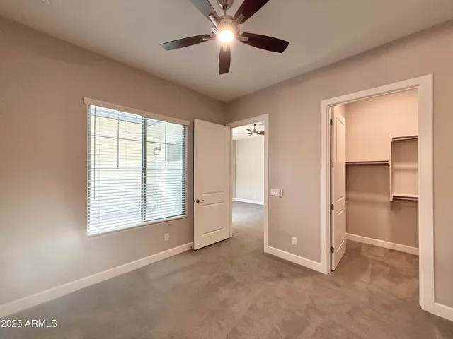 a view of an empty room with a window and a kitchen