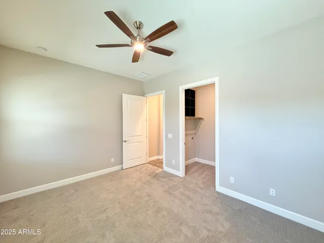 an empty room with closet and a ceiling fan