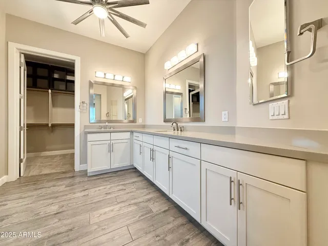 a large white kitchen with a large window wooden floor and stainless steel appliances
