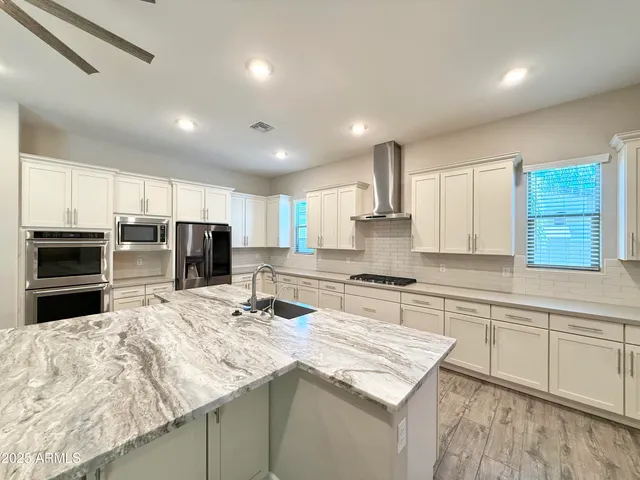a kitchen with stainless steel appliances kitchen island granite countertop a sink stove and refrigerator