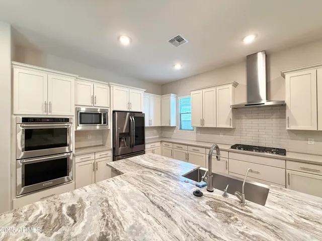 a kitchen with granite countertop a stove a sink and a refrigerator