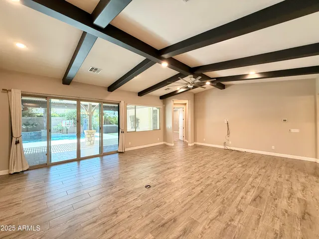 en empty room with wooden floor and windows