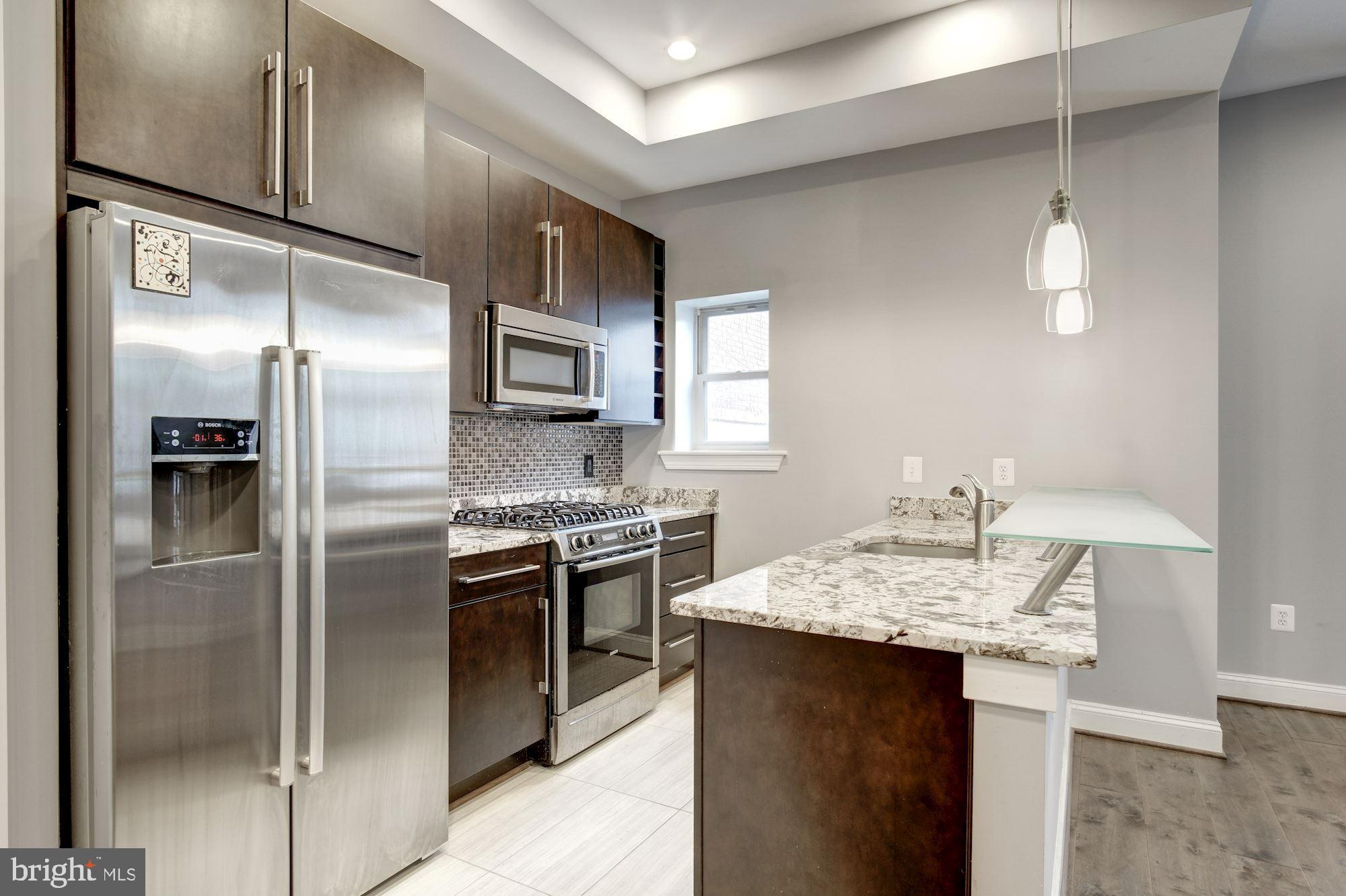1333 Euclid Street Northwest, Unit 202 Washington, DC 20009 - Photo 2 of 14 a kitchen with kitchen island granite countertop stainless steel appliances a sink stove and refrigerator