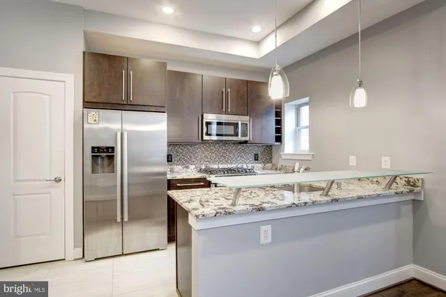 a kitchen with stainless steel appliances granite countertop a sink and a refrigerator