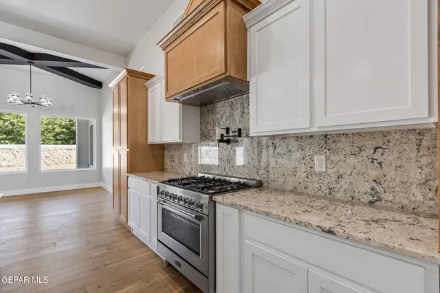 a kitchen with granite countertop cabinets a stove a sink and a window