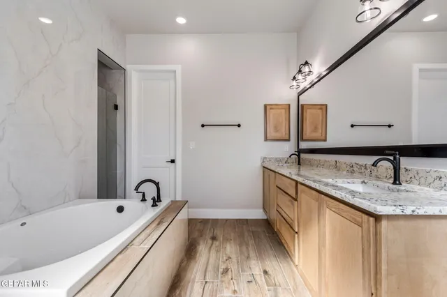 a bathroom with a granite countertop tub sink and mirror