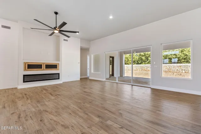 a view of an empty room with a window and wooden floor