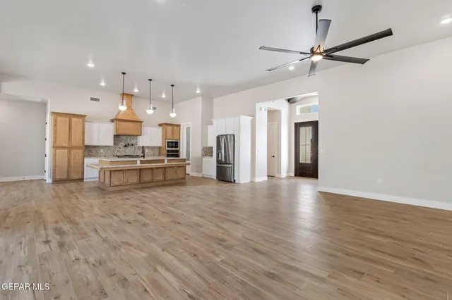 a view of kitchen with kitchen island wooden floor and refrigerator