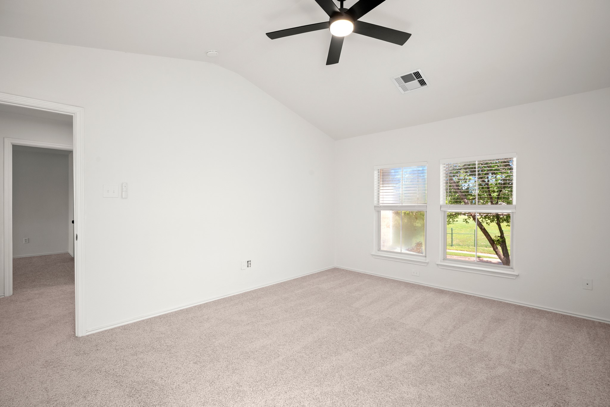 360 Sampson Kyle, TX 78640 - Photo 15 of 36 Carpeted room with a vaulted ceiling, two windows featuring blinds, and a ceiling fan with integrated lighting