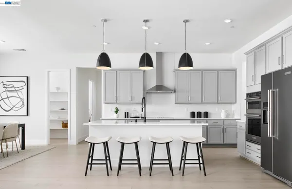 a kitchen with stainless steel appliances kitchen island granite countertop a table chairs in it and white cabinets