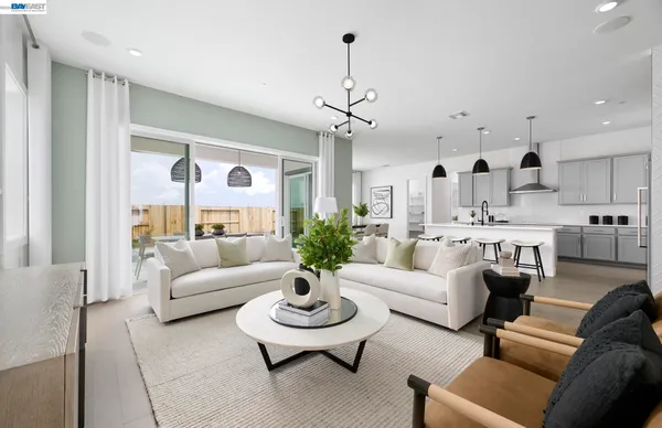 a living room with furniture kitchen view and a chandelier